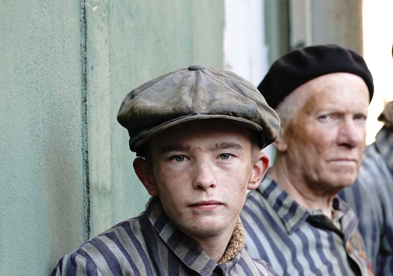 Bonhoeffer film still: a young prisoner and an older prisoner in striped uniforms